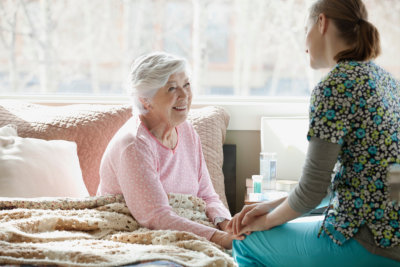 caregiver holding the hands of an erderly woman