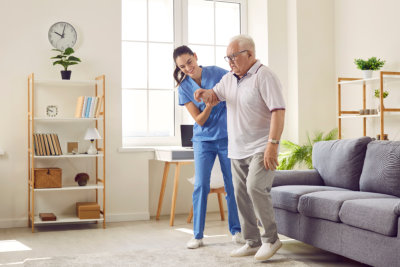 a caregiver helping an erderly man to walk