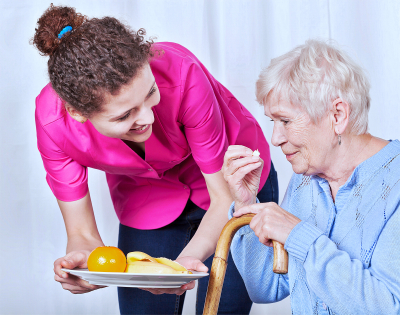 caregiver serving food to an elder woman