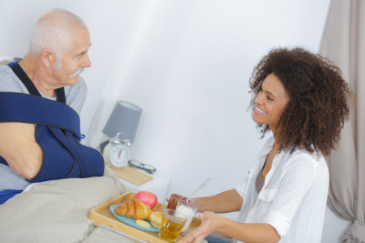 caregiver serving a meal to an elderly man